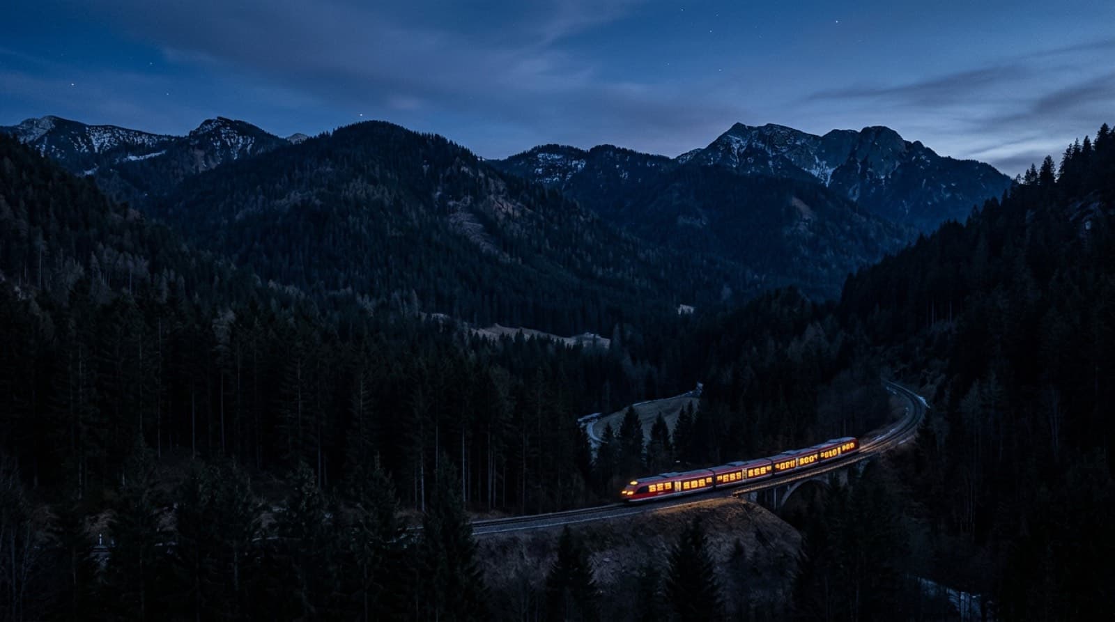 Un tren regional alemán cruzando un valle boscoso al anochecer