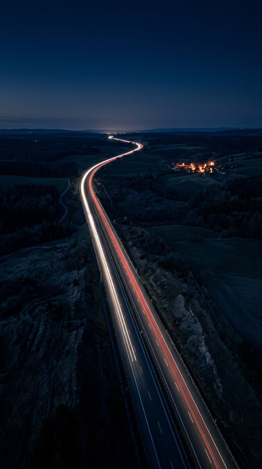 Una autopista europea de noche vista desde arriba, cruzando un paisaje oscuro