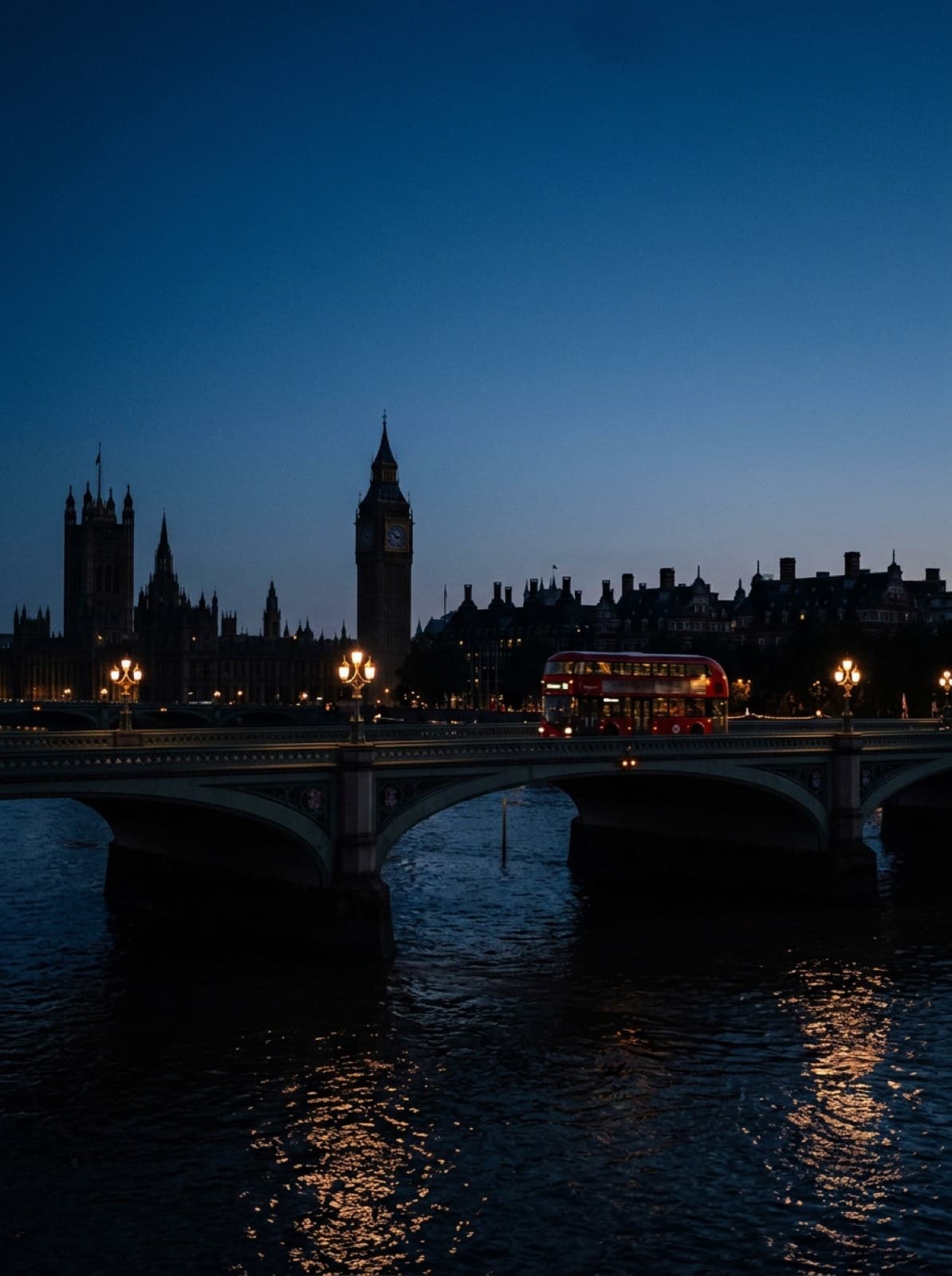 Un autobús rojo de dos pisos cruzando un puente de Londres en la hora azul
